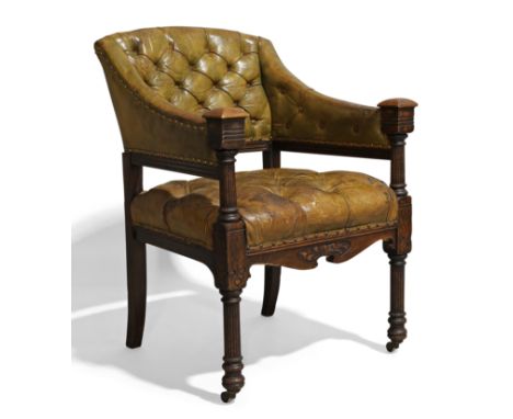An oak library armchair, c.1900, with brass nail decorated green leather button back upholstery, the sloping arms to block re