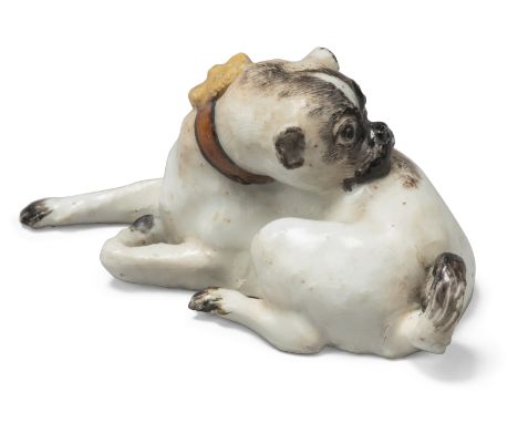 A Meissen porcelain small model of a pug dog, c.1740, in recumbent pose, its head turned to preen itself, a red collar around