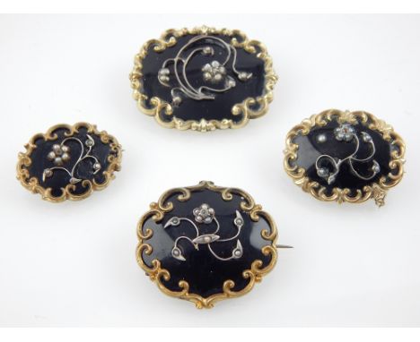 Four memoriam scroll frame brooches, black enamel with seed pearl floral decoration. (4) 
