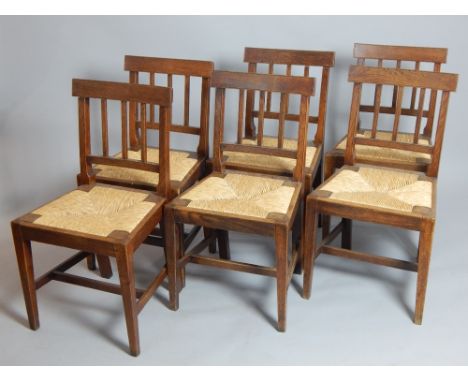 A set of six early 19th C oak dining chairs with square section stick backs over rush seats. (6) 