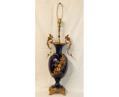 French decorated vase converted to table lamp, gilt brass cherub finials, sprig of flowers to body and set on brass scroll fe