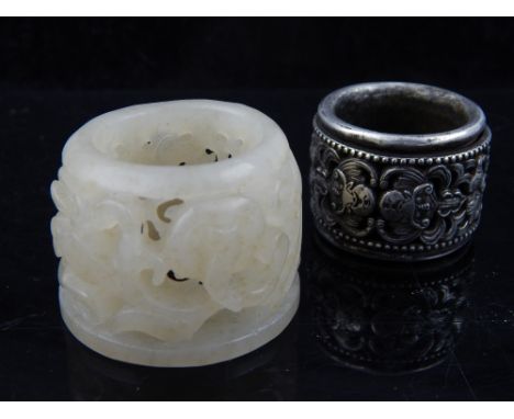 A Chinese white metal archer's thumb ring with revolving scroll decoration, and a jade archer's ring of pierced design  