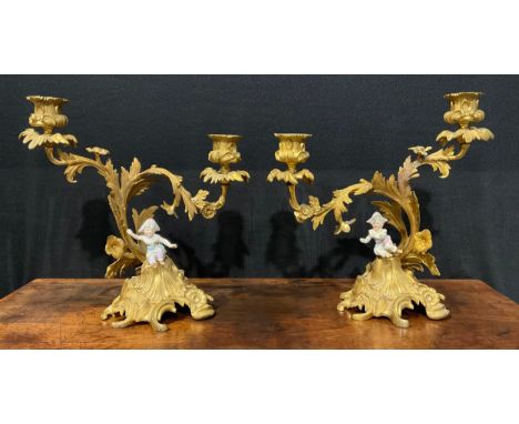 A pair of Rococo Revival gilt metal two-light candelabra, each cast with flowers and scrolling acanthus, the domed bases cres