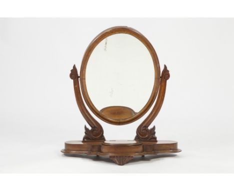 VICTORIAN CARVED MAHOGANY TOILET MIRROR, the oval plate in a moulded frame, flanked by scroll supports with foliate scroll ca