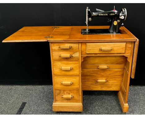 A vintage cast iron Singer Sewing machine, model number Y8364231, with walnut work-table / haberdashery cabinet, on casters; 