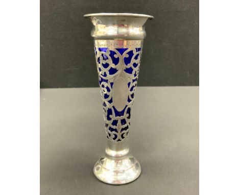 An Edwardian silver and blue glass trumpet form bud vase, pierced scrolling body, stepped foot, 18cm high, Chester 1904, weig