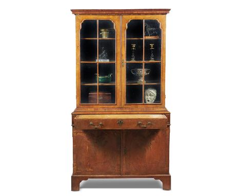 A George I walnut secretaire cabinet bookcase, circa 1720, the moulded cornice above a pair of glazed doors, opening to three