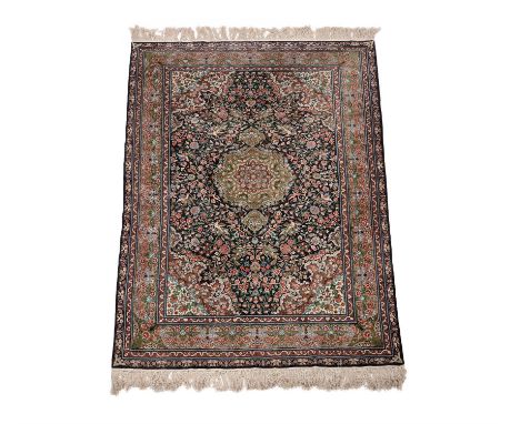 An Indian wool and silk rug, in Kashan style, decorated with birds perching in floral vines throughout, the dark field with a