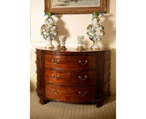 A George III mahogany and crossbanded semi elliptical commode, circa 1780, the shaped top above a slide and three banks of dr