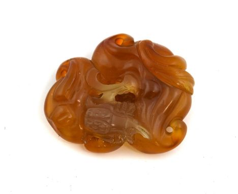A Chinese Hardstone Carving, as a fruit on an amber-coloured leaf-scroll ground4.5cm long