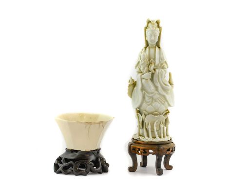 A Blanc de Chine Figure of Guanyan, Qing Dynasty, of traditional form seated holding a child, waterlilies at her feet21cm hig