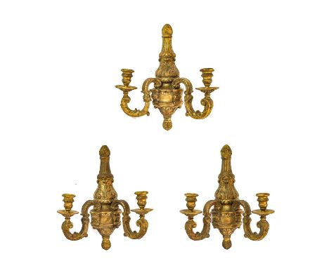 A Set of Three Giltwood and Gesso Twin-Light Wall Sconces, in Louis XIV style, with urn sockets, circular drip pans, leaf and