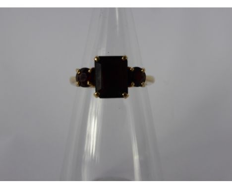 A 9 Ct Yellow Gold Garnet Ring. Centre stone 9 x 7 mm, 2 x 4.5 mm size P, approx wt 4 gms.