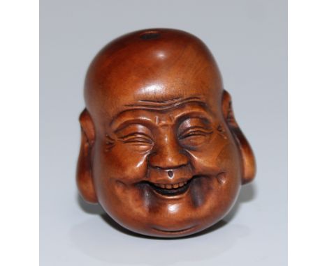 A Japanese boxwood netsuke, carved as the head of Buddha, smiling, 4cm long, signed 