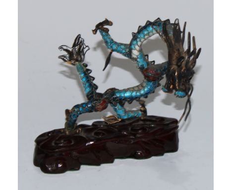 A Chinese silver coloured metal and enamel model, of a ferocious dragon, carved hardwood base, 12cm long 