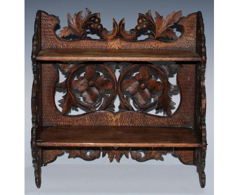 A Black Forest table-top two-shelf bookcase, the hinged sides restrained by hook-and-loops, carved in relief with leafy scrol