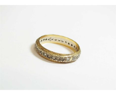 A white stone set eternity ring, the faceted stones claw set in white metal within two yellow metal bands, the shank stamped 