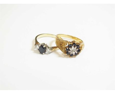 A 9ct gold three stone sapphire and diamond ring, the central oval mixed cut sapphire claw set in white gold and flanked to e