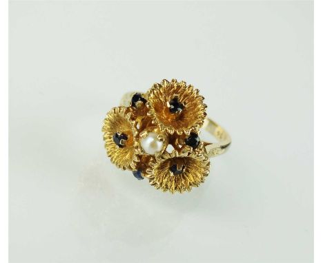 A single seed pearl and sapphire dress ring, designed as a central raised seed pearl claw set within three textured flowers w