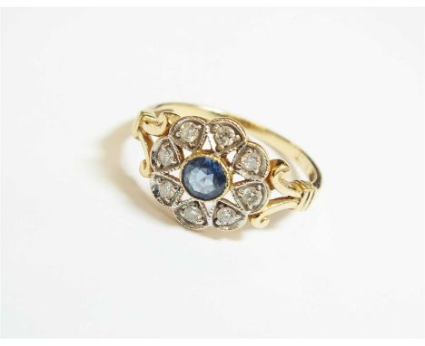An early 20th century sapphire and diamond floral cluster ring, designed as a central round mixed cut sapphire collet set in 