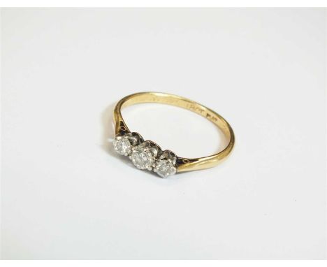 A three stone diamond ring, the three graduated brilliant cut diamonds claw set in white metal to yellow metal shank, stamped