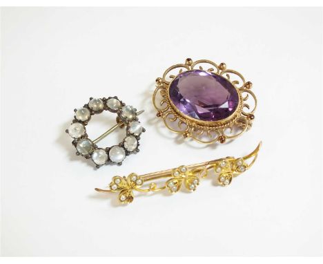 A collection of three brooches, comprising; an oval amethyst example within 9ct gold scroll and bead mount, 30mm wide, a circ