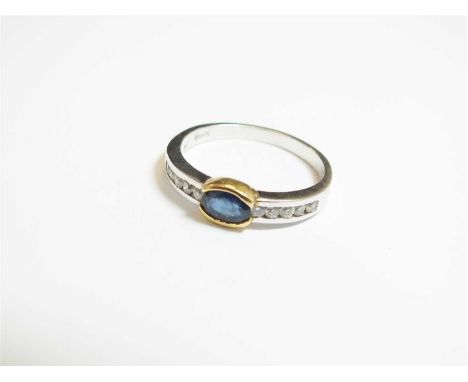 A sapphire and diamond ring, designed as a central oval mixed cut sapphire channel set in yellow metal and mounted to diamond