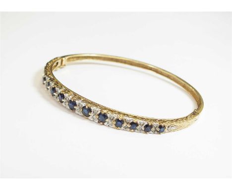 A 9ct gold sapphire and diamond hinged bangle, designed as eleven graduated mixed cut sapphires interspersed with twenty-two 