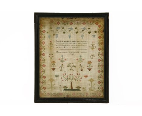 A George III needlework sampler, decorated with a floral border, grapevines, birds, flowers, and figures standing beneath a t