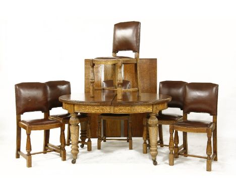 A large 20th century oak oval wind out extending dining table on turned tapering legs and ceramic casters, together with six 
