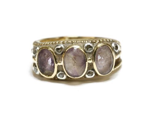 A gold three stone amethyst ring, with diamond set points, all rub set, marked 18ct, tested and valued as 18ct gold, (one sto