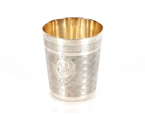 A small white metal continental beaker having engine turned and Greek key decoration with central monogram approx. 7.5cm high