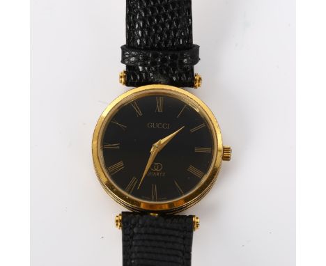 GUCCI - a lady's gold plated quartz wristwatch, black dial with Roman numeral hour markers and black enamel monogram case, ca