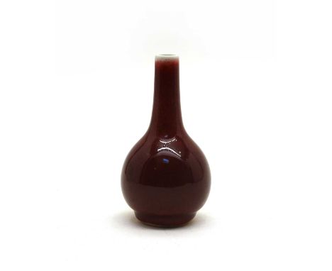 A Chinese red-glazed vase, the pear-shaped body rising on a circular foot, covered with a glaze of deep crushed strawberry co