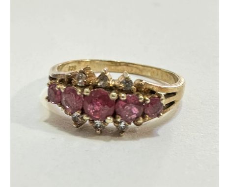 A yellow metal five stone graduated ruby and six stone white sapphire ring mounted in claw setting, the centre stone approxim