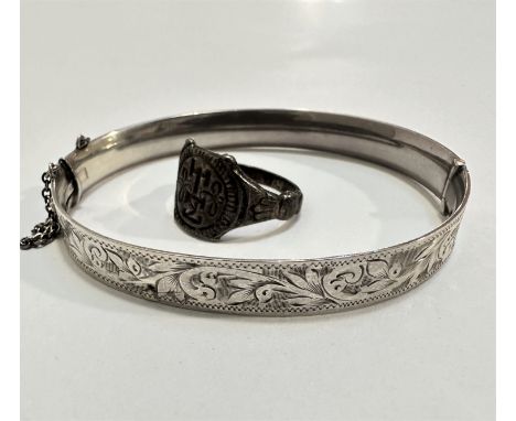 An Edwardian silver engraved stiff hinged bangle complete with safety chain, (d 7cm) with crest, inscription Henril 1565 Darn