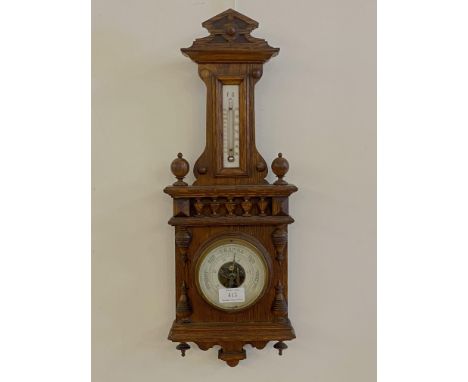 A late 19th century oak wall hanging aneroid barometer and thermometer with ivorine registers H54cm