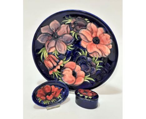 A William Moorcroft circular dish decorated with anemone design with blue ground (d 26cm), impressed mark and painted initial