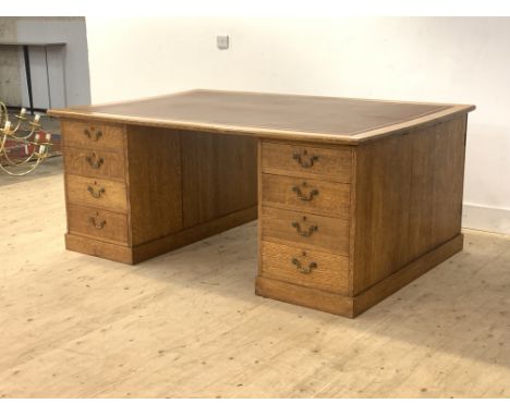 A large oak partners desk, early 20th century, the top inset with a gilt tooled skiver writing surface over two banks of four