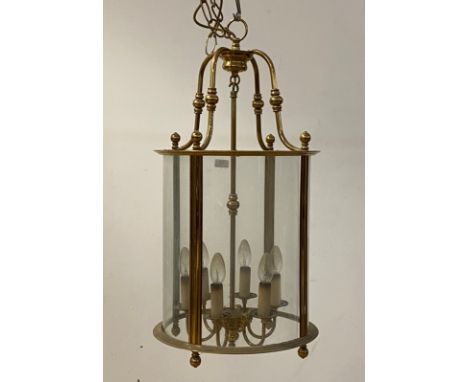 A gilt lacquered brass hall lantern of cylindrical form, the case suspended from four scrolled stretchers, with four glass pa