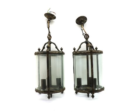 A pair of George III style three light hall lanterns,of recent manufacture, the cast metal frames holding three curved glass 