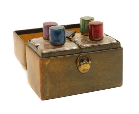 A cased set guilloche enamel topped glass bottles,comprising four bottles, of rectangular form, with blue, purple, green and 