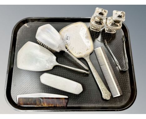 A silver four-piece dressing table set, further silver plates mirror and comb, a pair of plated tongs and pair of sifters. 