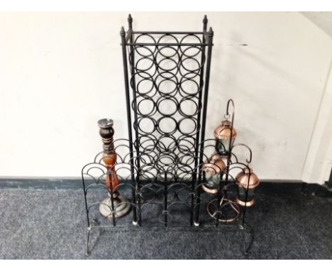 A wrought metal wine rack, similar candle holder, candlestick and a set three copper lanterns 