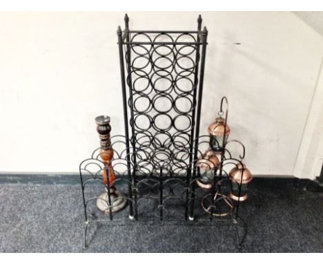 A wrought metal wine rack, similar candle holder, candlestick and a set three copper lanterns 