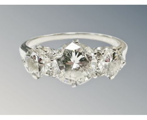 A platinum three stone diamond ring, the principal stone weighing 1.17 carat, flanked by two stones weighing 0.35 carat each,