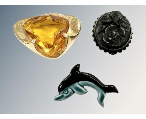 A Victorian jet mourning brooch 34.47 mm x 39.80 mm together with a ceramic Poole dolphin and a gold-tone 1980's brooch. (3)