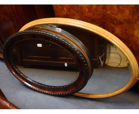 AN OVAL WALL MIRROR in a light wood frame, together with another in a moulded frame 