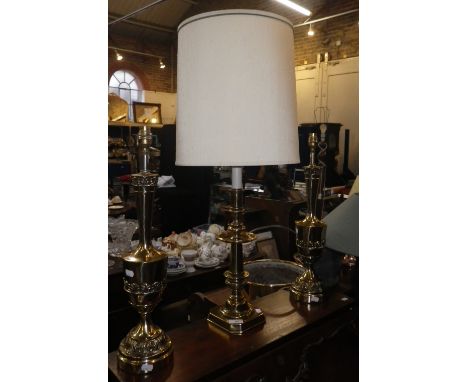 A PAIR OF BRASS TABLE LAMPS and a similar lamp in the form of a large candlestick, (shades below)