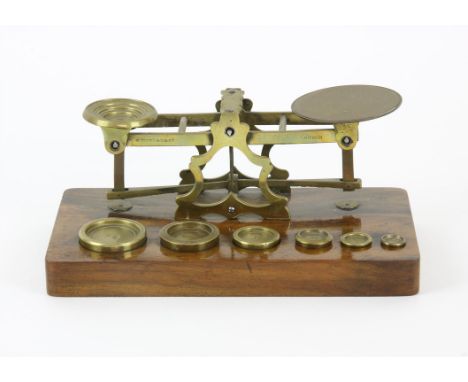 Brass postal weighing scales on rosewood stand complete with 6 weights from 1/8 an oz to 4 ozs 
